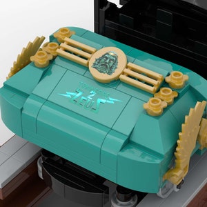 K&ouml;nnte beinhalten: Eine t&uuml;rkisfarbene Lego-Zuglokomotive mit goldenen Akzenten und dem Schriftzug "Thunderbolt Zeus" auf der Seite. Die Lokomotive hat ein goldenes Zahnrad an der Seite und ein goldenes Gesicht mit Bart an der Vorderseite.