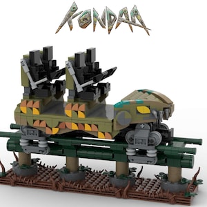 May include: A green, brown, and yellow Lego model of a roller coaster car with the word "KONDOR" in the background. The car has a snake-like design with a yellow eye and sharp teeth.