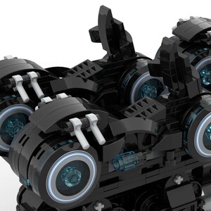 May include: A black and silver toy vehicle with multiple wheels and blue glowing lights. The vehicle has a futuristic design and is made of plastic.