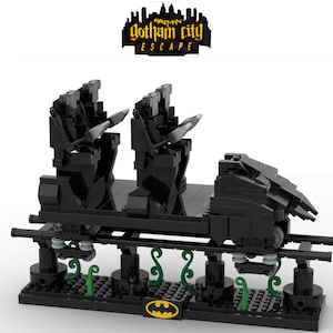 Könnte beinhalten: Schwarzes Lego-Modell eines Achterbahnwagens mit zwei Sitzen, einer Fledermaus-förmigen Front und einem Batman-Logo auf der Basis. Der Wagen befindet sich auf einer Schiene mit grünen Pflanzen an den Seiten. Der Text "Gotham City Escape" befindet sich über dem Wagen.