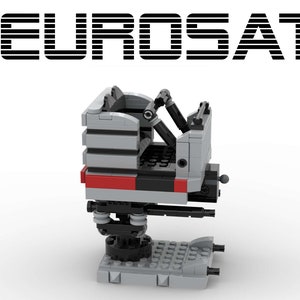 May include: A gray and black Lego model of a satellite dish with a red stripe. The model is on a gray base with black wheels.