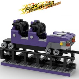 May include: A purple and black toy roller coaster with the text "Rock 'n' Roller Coaster Aerosmith" above it. The coaster has two rows of seats and sits on a black track. The wheels are grey.
