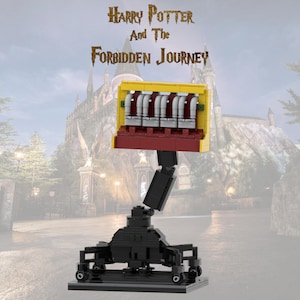 May include: A Lego model of the Harry Potter and the Forbidden Journey ride. The model features a yellow and red car with silver seats, mounted on a black articulated arm and base. The text "Harry Potter And The Forbidden Journey" is above the model.