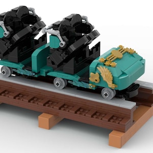 K&ouml;nnte beinhalten: Ein t&uuml;rkisfarbener und schwarzer Lego-Achterbahnwagen mit goldenen Akzenten. Der Wagen befindet sich auf einer braunen Holzschiene.