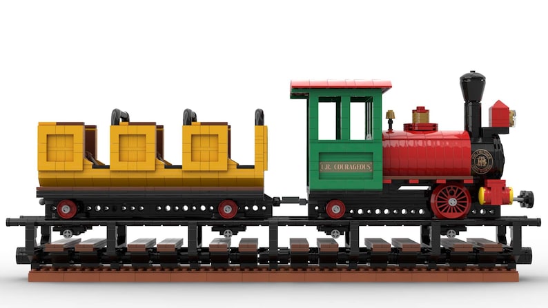 May include: A red, green, and yellow toy train with a black engine and three yellow passenger cars. The train is on a brown track and the engine has the text "C.R. COURAGEOUS" on the side.