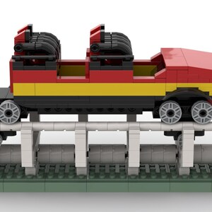 May include: A red, yellow and black Lego roller coaster train with two carriages and a track.
