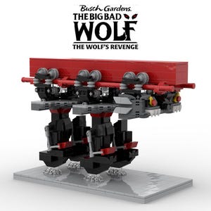May include: A Lego model of a roller coaster car, featuring a red top section and black supports. The model includes gray and red details, with a wolf-like design on the front. The text "Busch Gardens. THE BIG BAD WOLF THE WOLF'S REVENGE" is visible above.