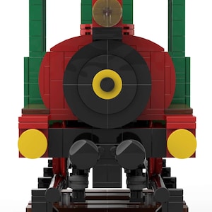 May include: A red, green, and black toy train engine with yellow headlights and a black wheel. The train is on a brown track.