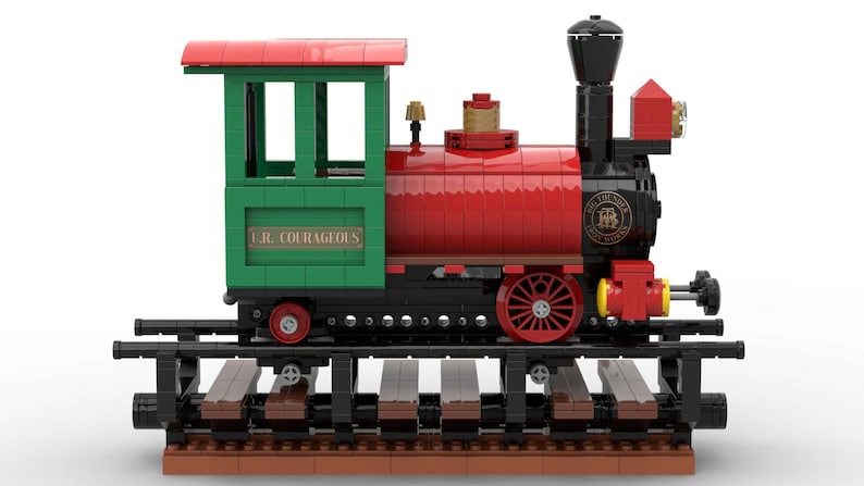 May include: A red and green toy train with a black chimney and wheels. The train is on a track and has a sign that says "L.R. COURAGEOUS".