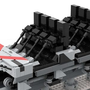 Pu&ograve; includere: Modello dettagliato di una carrozza di montagne russe, costruito con blocchi ad incastro. La carrozza presenta una combinazione di colori grigio e bianco con accenti rossi e sedili neri. Il modello include ruote e strutture di supporto, suggerendo ingegneria e design.