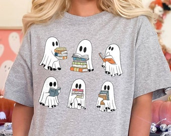 May include: A gray t-shirt with a graphic of six ghosts reading books. The ghosts are white and have different expressions on their faces. The books are stacked and have different colors.