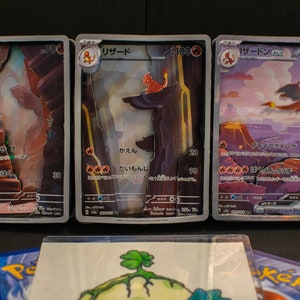 Könnte beinhalten: Drei Pokémon-Sammelkarten mit Glurak, Glutexo und Glurak. Die Karten sind in Japanisch und zeigen Illustrationen der Pokémon in einer feurigen Landschaft.