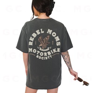 May include: A dark gray t-shirt with a graphic print on the back. The graphic features a vintage-style eagle with the text "Rebel Moms The American Motorbike Society Strong Dignified".