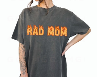 May include: A charcoal gray t-shirt with the text "RAD MOM" in orange and yellow letters with flames on top of the letters.