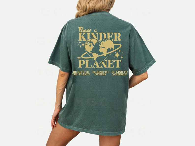 Peut inclure: Un t-shirt vert avec un graphique d'une plan&egrave;te en forme de c&oelig;ur avec le texte "Create a Kinder Planet" et "Be kind to the planet, be kind to others, be kind to yourself".
