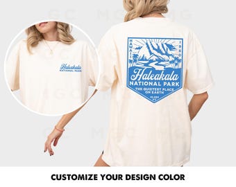 May include: A white t-shirt with a blue graphic design featuring a mountain range and the text "Haleakala National Park, The Quietest Place on Earth, 10,023 ft".