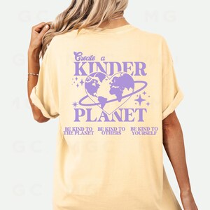 Peut inclure: Un t-shirt jaune avec un motif violet qui dit "Cr&eacute;er une plan&egrave;te plus gentille" avec une terre en forme de c&oelig;ur et le texte "Soyez gentil avec la plan&egrave;te, soyez gentil avec les autres, soyez gentil avec vous-m&ecirc;me."