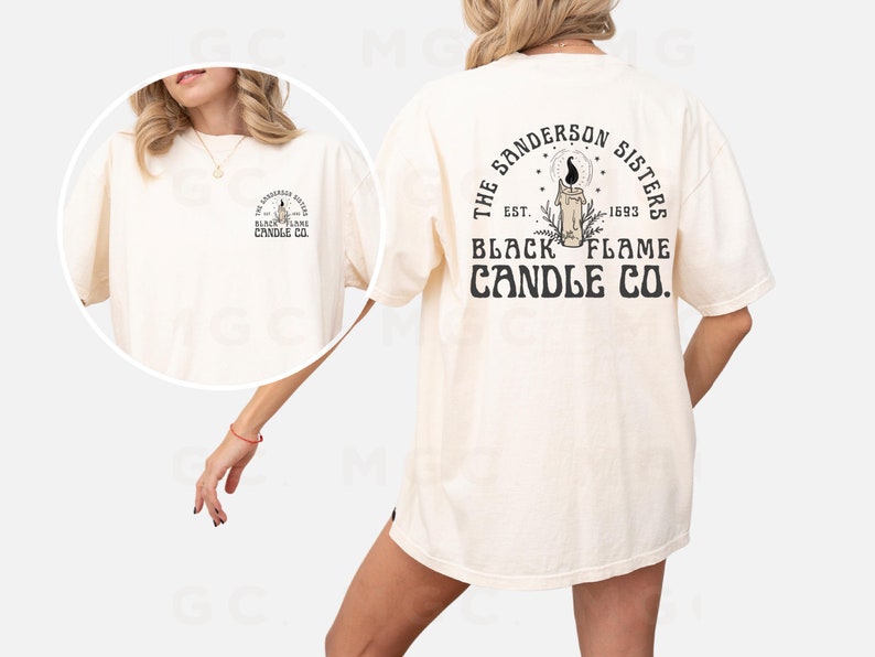 Pu&ograve; includere: Una t-shirt color crema con una stampa grafica sul retro che dice "The Sanderson Sisters Est. 1693 Black Flame Candle Co."