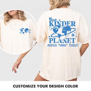 Peut inclure: Un t-shirt blanc avec un graphique bleu qui dit "Cr&eacute;er une plan&egrave;te plus humaine" et repr&eacute;sente une terre en forme de c&oelig;ur avec des &eacute;toiles. Le texte sous le graphique dit "Soyez gentil avec la plan&egrave;te, Soyez gentil avec les autres, Soyez gentil avec vous-m&ecirc;me."