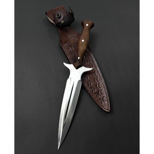 May include: A silver dagger with a brown wooden handle and a leather sheath. The dagger has a double-edged blade with a pointed tip.