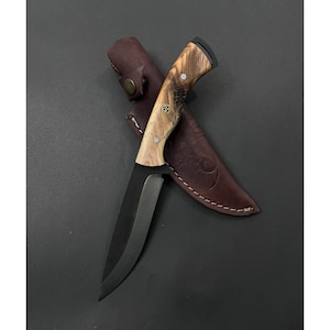 Könnte beinhalten: Ein Messer mit schwarzem Griff, einem Holzgriff und einer Lederscheide. Das Messer hat eine schwarze Klinge und einen Holzgriff mit natürlicher Holzmaserung.