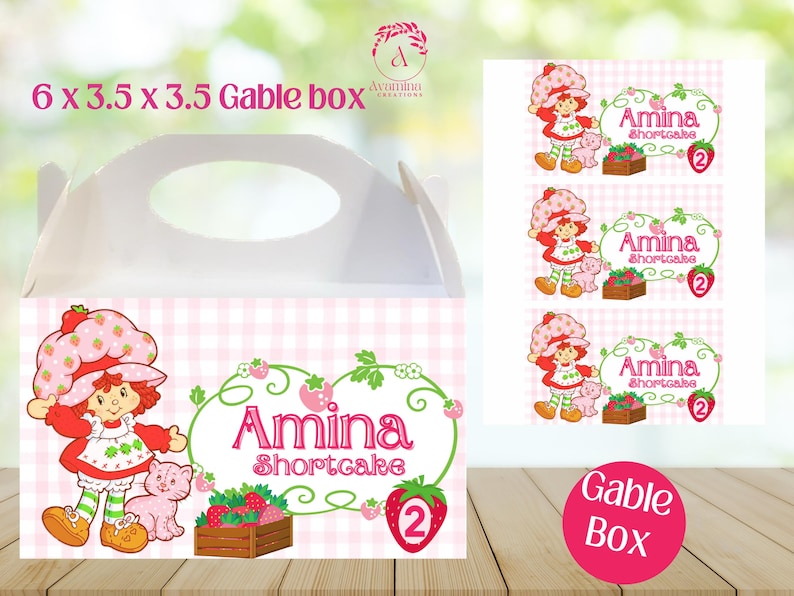 May include: White gable box with a handle, featuring a pink and white checkered pattern. The box is decorated with a cartoon strawberry girl, the name "Amina Shortcake", and the number 2. The box measures 6 x 3.5 x 3.5 inches.