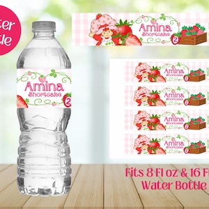 May include: A clear water bottle with a custom label featuring the text "Amina Shortcake" and a strawberry design. The label also includes the number "2". Additional labels are visible. The words "Water Bottle" are in a pink circle.