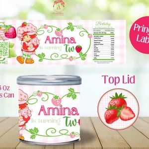 May include: A birthday-themed Pringles can label and lid featuring a strawberry theme. The can is decorated with a cartoon character and the text "Amina is turning Two". The label includes a QR code and nutrition facts.