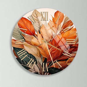 Puede incluir: Reloj de pared redondo con un diseño botánico de hojas naranjas, rojas y verdes. La esfera del reloj tiene números romanos y agujas doradas. El reloj se muestra sobre una cómoda de madera con dos jarrones amarillos.