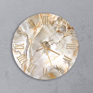May include: Round wall clock with a marble-like design in shades of white, beige, and brown. The clock features gold Roman numerals and hands, creating a stylish and elegant aesthetic. The clock is a decorative home decor item.