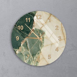 May include: A round wall clock featuring a split design of dark green and cream-colored marble patterns. The clock face displays gold-colored Arabic numerals from 1 to 12 and matching gold-colored hour, minute, and second hands. A jagged gold-colored line separates the two marble sections, creating a textured visual effect across the circular surface.