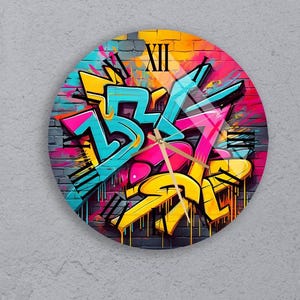 May include: A round clock with a graffiti design featuring colorful letters and drips. The clock face has Roman numerals and a gold-colored hour and minute hand.