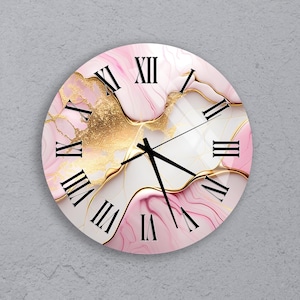 May include: Round wall clock with a pink, white, and gold abstract design. The clock face features black Roman numerals and black clock hands. The design has a marble effect with gold accents.