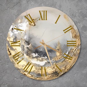 Może przedstawiać: Okrągły zegar z abstrakcyjnym wzorem w kolorze białym i złotym. Tarcza zegara ma cyfry rzymskie i złote wskazówki.