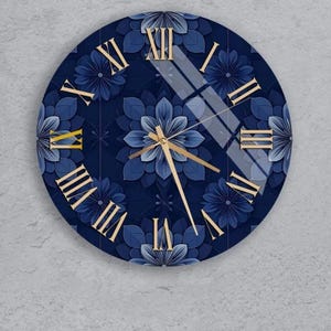 Pode incluir: Relógio de parede redondo com um design floral azul marinho. O mostrador do relógio apresenta algarismos romanos e ponteiros dourados. O padrão floral inclui vários tons de azul, criando um efeito em camadas. É um item decorativo.