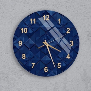 May include: A round, navy blue wall clock with a textured geometric pattern. The clock features gold-colored hands and numerals. The clock's face is covered with a glass panel. The clock is mounted on a gray wall.