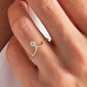 May include: A gold ring with a delicate, branching design and a single, clear gemstone in the center.