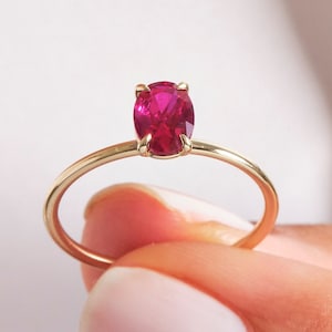 Puede incluir: Un anillo de oro con una sola piedra preciosa de rubí de forma ovalada.