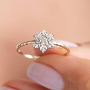 May include: A delicate gold ring with a flower-shaped center made of small, sparkling diamonds.