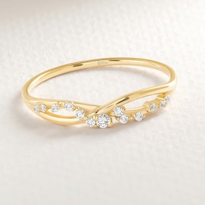 May include: A delicate gold band ring with a delicate, intertwined design accented with small, sparkling diamonds.