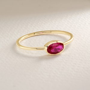 May include: A gold ring with a single oval-shaped ruby gemstone.