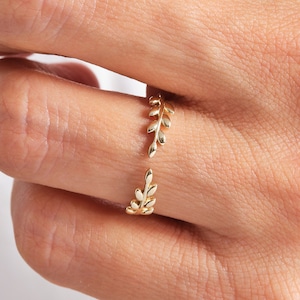 May include: A gold ring with a delicate leaf design. The ring is open and adjustable to fit different finger sizes.