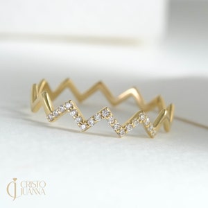 May include: A gold band ring with a zig-zag design set with small diamonds.