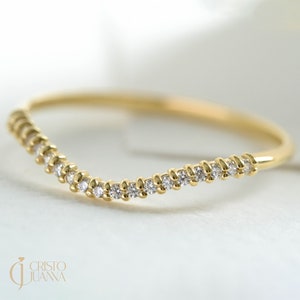 May include: A delicate gold band ring with a curved row of small diamonds.