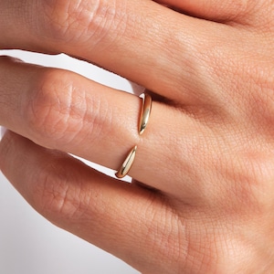 May include: A gold ring with two pointed ends. The ring is open and can be adjusted to fit different finger sizes.
