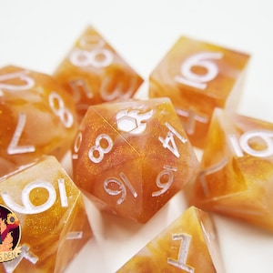 May include: A set of six orange and white dice with white numbers. The dice are made of a translucent material with a glittery finish.