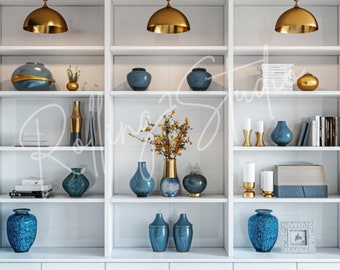 May include: A white built-in bookshelf with various decorative items. The shelves display blue and gold vases, books, and decorative objects. Three gold pendant lights hang above the shelves, illuminating the items. The overall aesthetic is modern and elegant.