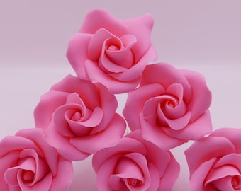 Op de afbeelding: Zes roze suikerrozen, elk met een delicate swirl in het midden, gerangschikt in een piramidevorm op een lichtroze achtergrond.