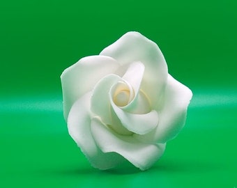 Puede incluir: Una sola rosa de azúcar blanca sobre un fondo verde.