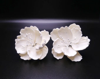 May include: Two white sugar flower blossoms with silver centers. The flowers are made of fondant and are perfect for decorating cakes and cupcakes.